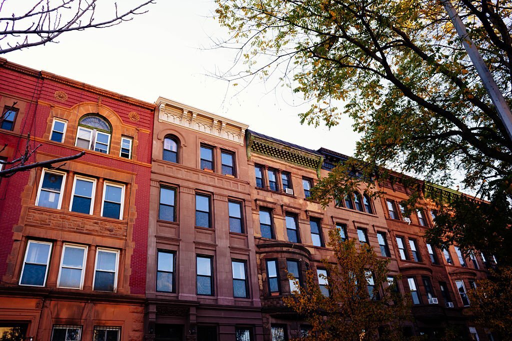 Colorful brownstones and townhouses line the treelined block.