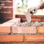 industrial Construction bricklayer worker building walls with bricks, mortar and putty knife